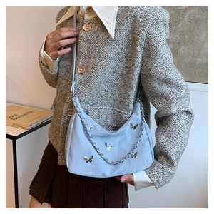 Détail du sac demi-lune bleu clair avec papillon argenté et petite chaîne décorative