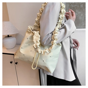 Detail of cream nylon tote bag featuring stylish ruched straps and silver rivet accents
