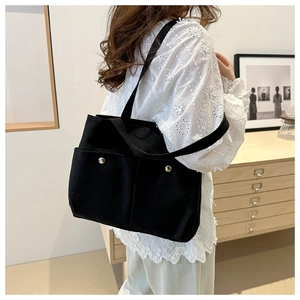 Close-up of black canvas tote bag showing external pockets and silver metal buckle details