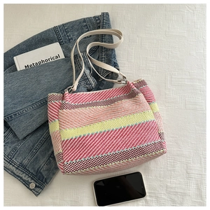 Détail du sac bandoulière tissé à rayures colorées avec des anses en cuir blanc sur tissu