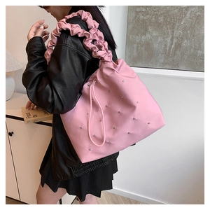 Detail of pink pleated handle shoulder bag with silver studs and drawstring closure