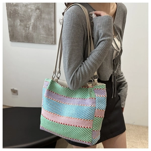 Détail d'un sac cabas en maille à rayures colorées avec bandoulière et anneau métallique