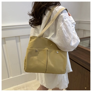 Detail view of mustard yellow canvas tote bag with dual front pockets and silver snap button