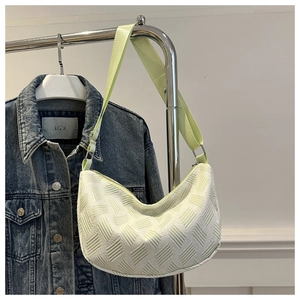 Close-up of light green half-moon bag with 3D woven texture and wide nylon strap