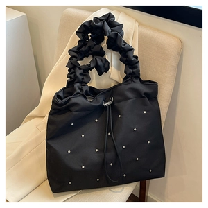 Close-up of black nylon tote bag featuring rhinestone studs and pleated ruffle shoulder strap