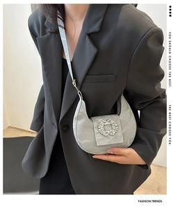 Detail of silver crescent bag with ruched texture and large rhinestone buckle detail
