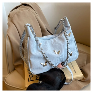 Détail du sac plissé bleu clair avec breloques papillon argentées et chaîne métallique