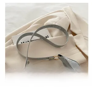 Detail of grey textured leather strap with premium gold metal buckles on a crescent bag