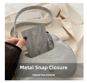 Macro shot of silver crescent bag with wrinkled texture and magnetic metal buckle
