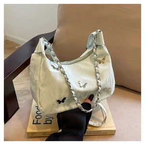 Détail du sac à bandoulière bleu clair avec papillons en métal et chaîne