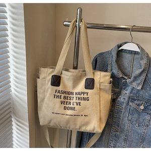 Détail du sac cabas en toile avec renfort en cuir marron et bandoulière réglable