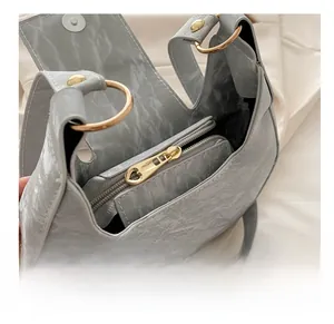 Detail of the gray crescent bag showing the smooth golden zipper and pleated texture