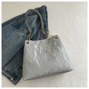 Detail der silbergrauen Tragetasche mit FASHION-Prägung und plissierter Textur