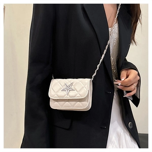 Close-up of a white quilted crossbody bag with a large rhinestone star on the cover