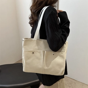 Minimalist cream canvas tote bag with large front pockets and wide straps for daily commute