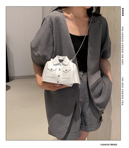 Close-up of a mini white jacket-shaped crossbody bag featuring silver buttons and pockets