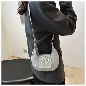 Detail of silver crescent shoulder bag with pleated texture and sparkling crystal buckle