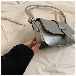 Detailed close-up of metallic silver shoulder bag featuring vertical stitching and knot strap