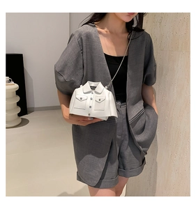 Close-up of white creative jacket-shaped shoulder bag with silver chain on a grey blazer