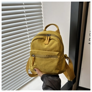 Close-up of mustard yellow nylon mini backpack with adjustable straps and front pocket