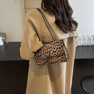Sac bandoulière léopard avec chaîne métallique porté par un mannequin dans un café