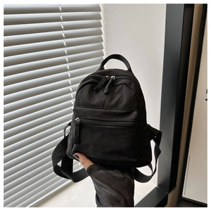 Detail of a black nylon mini backpack with top handle and adjustable fabric straps
