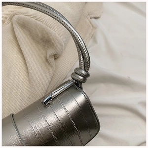 Macro shot of silver underarm bag featuring vertical texture and spiral knotted handle