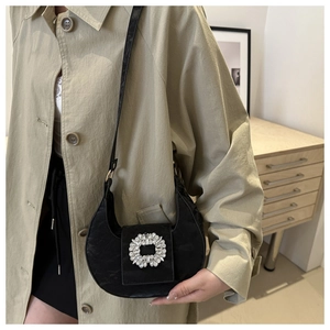 Detail of black crescent moon bag with vintage texture and oversized rhinestone buckle