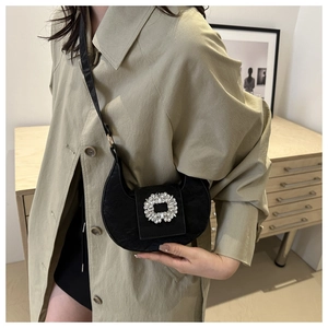 Detail of black crescent handbag featuring a large square rhinestone buckle and velvet texture