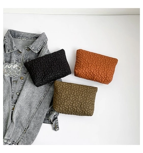 Detailed view of quilted nylon clutch bags in black, caramel, and olive with floral patterns