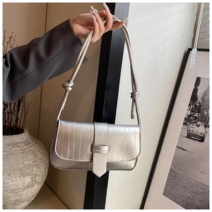 Detail of silver rectangular underarm bag with vertical ribbed texture and knot strap