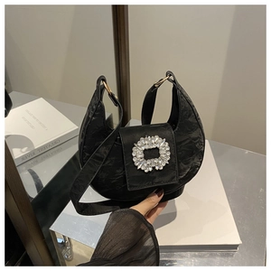 Detail of black pleated hobo bag with a large rhinestone buckle and crescent shape