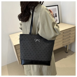 Detailed view of black heart print tote bag with metallic bow on a model in a room