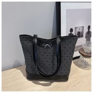 Close-up of heart patterned tote bag with black leather base and silver bow detail