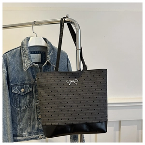 Detail of grey heart print tote bag with silver bow charm and black leather straps
