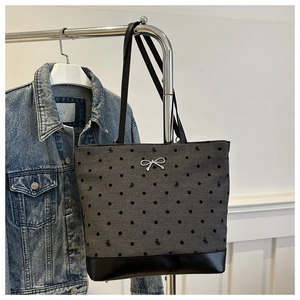 Detail of grey canvas tote bag with black bow print and silver bow pendant charm
