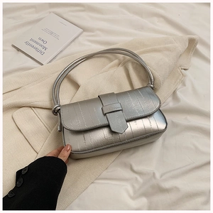 Macro detail of silver metallic square shoulder bag with vertical embossed striped texture