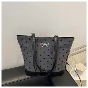 Close-up of gray polka dot tote bag with silver metal bow and black leather handles