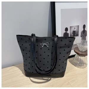 Detail of grey tote bag with bow embroidery and silver metal hardware on wooden table