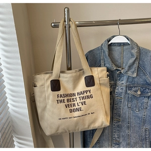 Détail du sac fourre-tout en toile montrant le renfort en cuir et la poche latérale