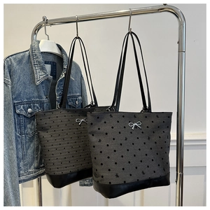 Detail of dark gray canvas tote bags with bow ribbon and black faux leather base