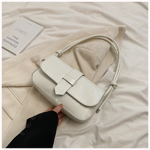 Detail of white crocodile embossed leather underarm bag with knot strap on beige knitwear