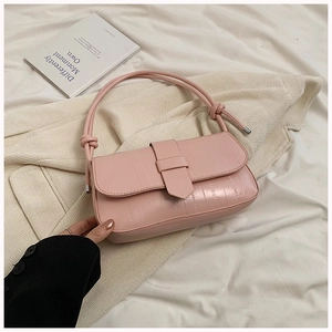 Close-up of pink textured faux leather baguette bag with knot strap and stylish buckle