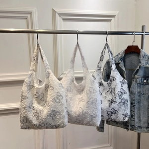 White butterfly print lace tote bag with textured fabric and fringe edge on a hanger