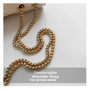 Detailed macro view of the golden box chain strap on a cream white leather handbag