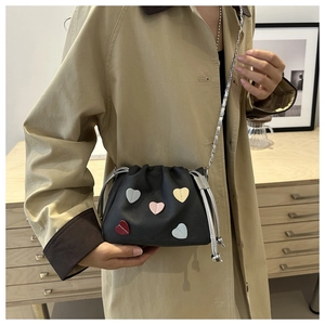 Detail of black PU leather bucket bag with colorful heart patches and silver chain strap