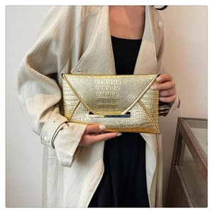 Detail view of the golden envelope clutch bag featuring a crocodile-embossed leather texture