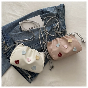Detail of trendy drawstring cloud buckets in beige and pink with heart patches and chains