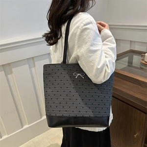 Large capacity heart print tote bag with metal bow accent shown on model in a casual setting