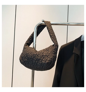 Détail de la texture matelassée florale noire sur un sac à main léger pour femme
